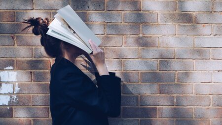 en kvinna håller en bok framför ansiktet